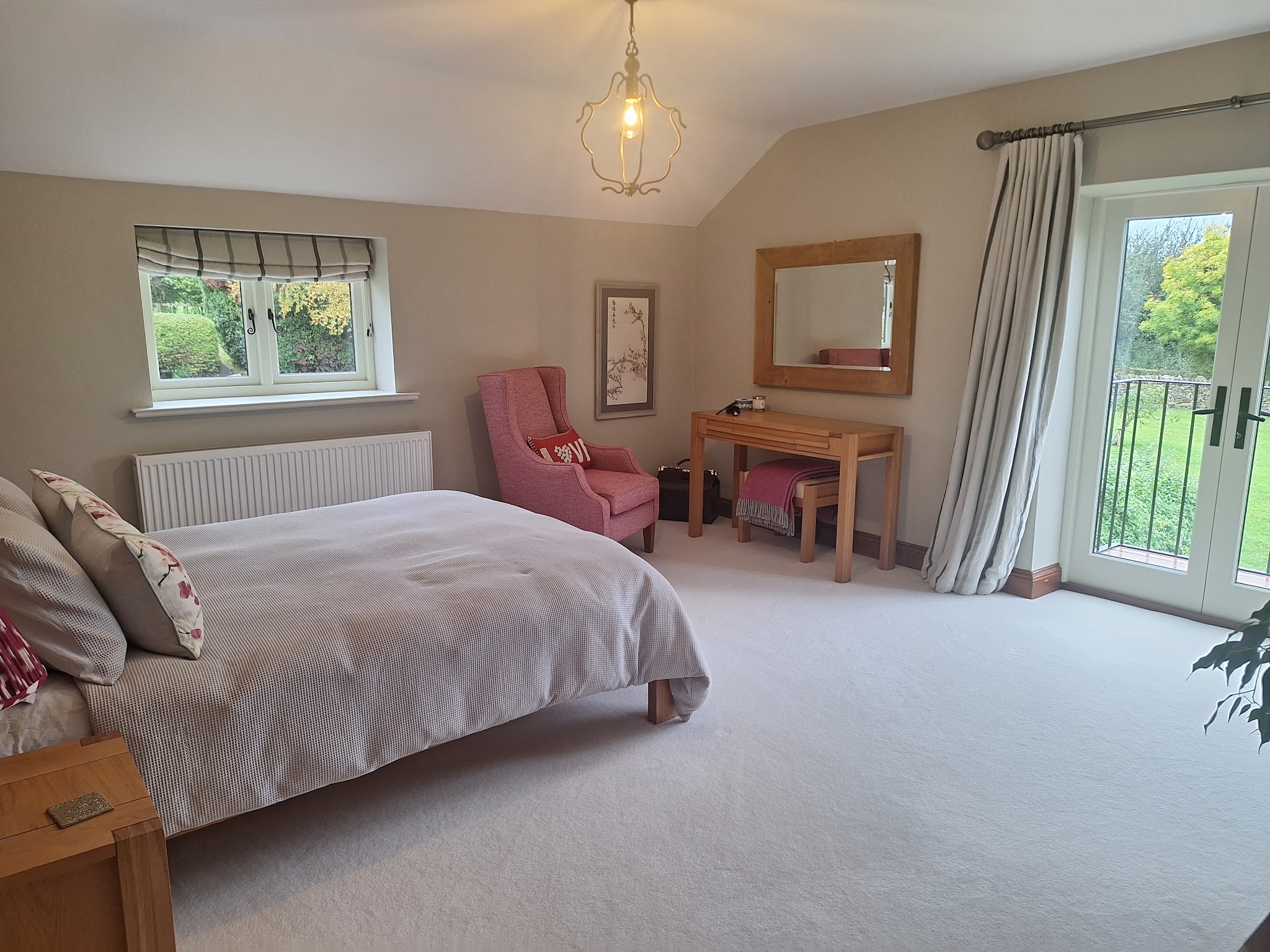 A finished bedroom with soft neutral walls, white woodwork and French doors onto the garden